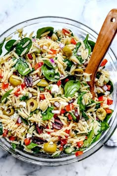 pasta salad with spinach, olives and feta cheese in a glass bowl