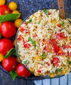 a bowl filled with rice and tomatoes next to some other vegetables on a table top