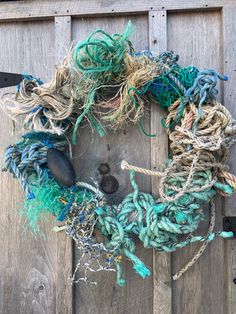 a wreath made out of rope and other items hanging on a wooden door with a pair of scissors