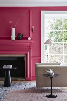 the living room is painted bright pink and has two chairs, a coffee table, and a fireplace