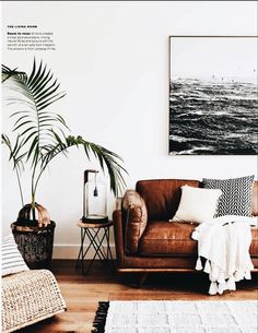 a living room with a brown leather couch and white rugs on the wooden floor