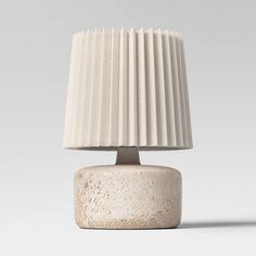 a white table lamp sitting on top of a wooden base