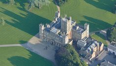 an aerial view of a large building in the middle of a green field with lots of trees