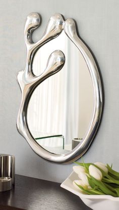 a mirror that is on the side of a wall next to a vase with flowers