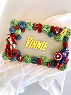 a decorated cake with the name winnie written on it and captain america figures in the middle