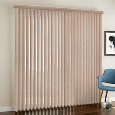 a living room with a blue chair and large window covered in beige vertical blind blinds