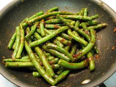 green beans are being cooked in a frying pan