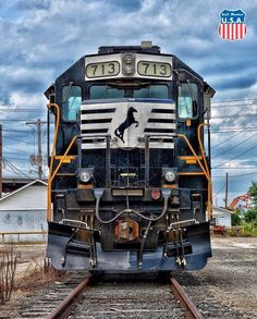 an old train is sitting on the tracks in front of some buildings and power lines