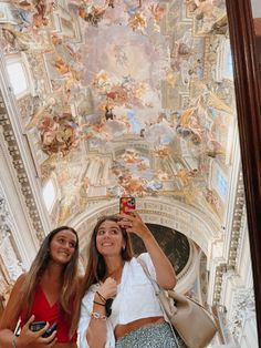 two women taking a selfie in front of a painted ceiling