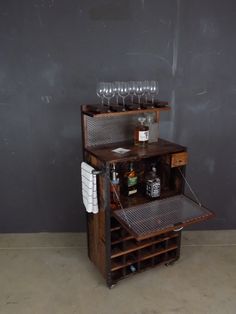 a wine rack with bottles and glasses on it in front of a gray wall,