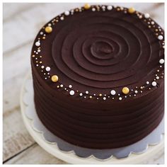 a chocolate cake with white and gold sprinkles sits on top of a plate