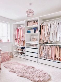 a white closet filled with lots of pink and white clothes next to a baby's crib