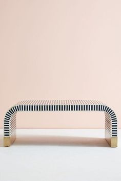 a black and white bench sitting in front of a pink wall on top of a floor