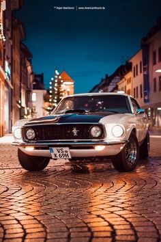 an old ford mustang parked on the street at night