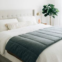 a bed with white sheets and pillows in a bedroom