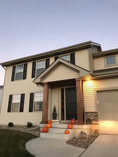 a house with white siding and black shutters on the front door is shown at dusk