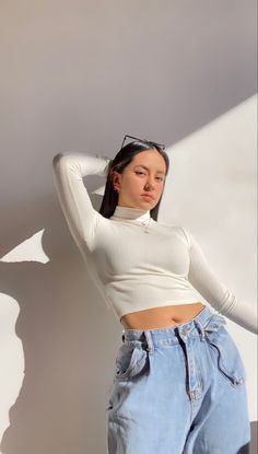 a young woman is leaning against a wall with her arms behind her head and looking off to the side