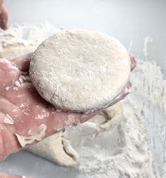 a person holding a doughnut in their left hand and powdered sugar on the other