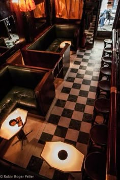 the interior of a restaurant with black and white checkered flooring, leather booths, and tables