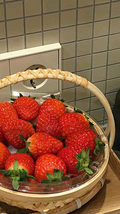 a basket full of strawberries sitting on top of a table next to a microwave