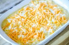 a casserole dish with cheese and sour cream in it on a wooden table