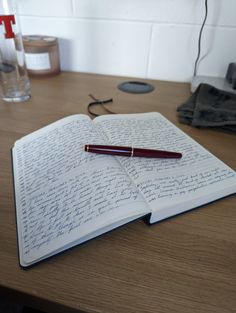 an open notebook with writing on it and a pen resting on the page next to it