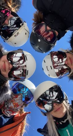 four people wearing helmets and goggles standing in a circle