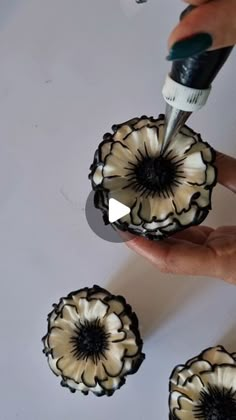 a person is painting flowers with white and black paint