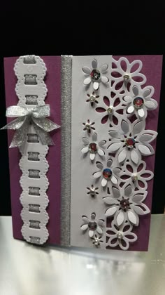 a close up of a greeting card with flowers and ribbons on the front, and an embellishment in the back