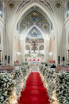 the inside of a church with red carpet and white flowers