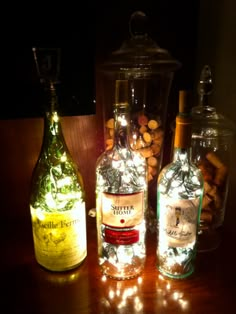 three bottles with lights in them sitting on a table