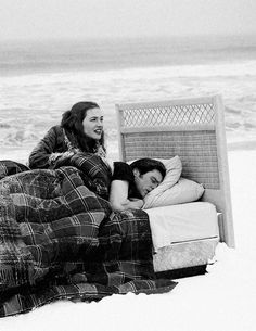 two people laying in bed on the beach