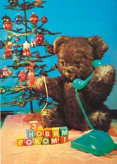 a brown teddy bear sitting next to a christmas tree