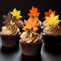 cupcakes decorated with chocolate frosting and fall leaves on black table top, ready to be eaten