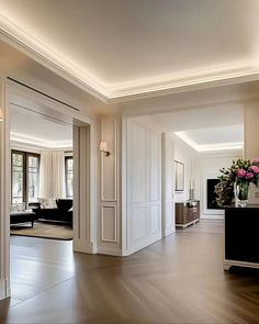 A modern hallway with white walls, crown molding, and wall panels. The floor is herringbone hardwood and there is recessed lighting in the ceiling. Hearing Bone Floor, Hallway Trim Molding, Ceiling Trim Molding, Modern Moldings And Trim, Hallway Molding, Modern Molding, Modern Panelling, White Crown Molding, Modern Crown Molding