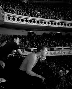 black and white photograph of two men playing tennis in front of an audience at a sporting event