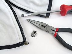 a pair of pliers and screwdrivers are laying next to a white jacket