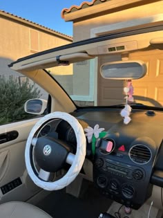 the interior of a car with stuffed animals on the dash board and steering wheel, in front of a house