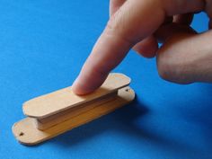 a hand is pointing at a piece of wood on a blue surface with a finger