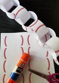 scissors, tape, and glue are sitting on top of paper with baseballs printed on it