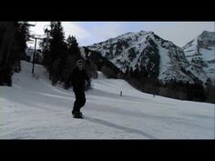 a man riding a snowboard down the side of a snow covered slope next to mountains