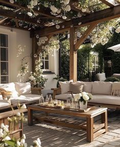 an outdoor living area with couches, tables and flowers on the pergoline