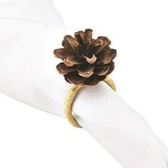 a pine cone is sitting on top of a white napkin with a gold ring around it