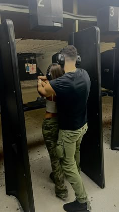 a man and woman are aiming at an object in the air with headphones on