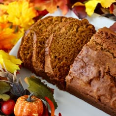 two slices of bread sitting on top of a white plate next to autumn leaves and pumpkins