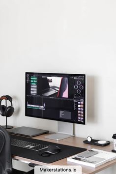 a computer monitor sitting on top of a desk next to a keyboard and headphones