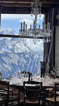 a dining room table with chairs and a chandelier hanging from it's ceiling