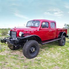 an old red truck is parked in the grass