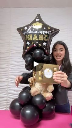 a woman is holding a teddy bear in front of balloons and a star balloon that says congratulations grad