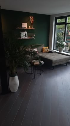 a living room filled with furniture and a large window next to a plant in a vase